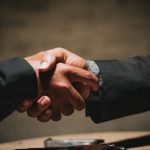 two people shaking hands over a wooden table