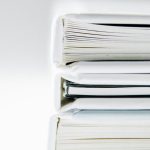 A stack of thick folders on a white surface